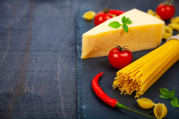 Spaghetti, cheese and chili peppers on a black background.