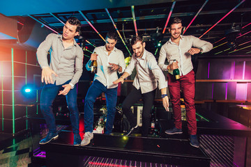 Group of smiling male friends having fun in night club