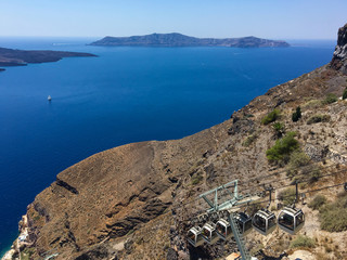 Funicular cable car slides down the mountain of a volcanic island against the background of the sea