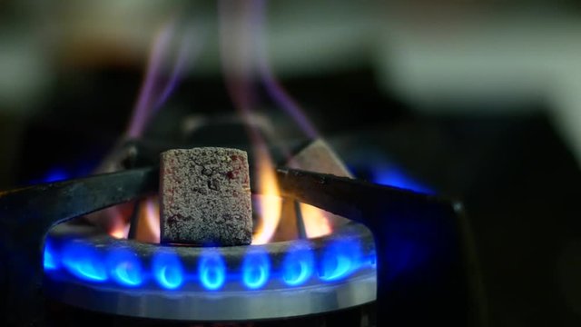 Coal for a hookah is heated on a gas burner