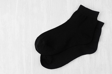 Pair blank black medium socks flat lay on white wood board, side view - mock up for design, print, presentation, advertising, top view, copy space.