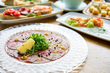 Beef carpaccio with balsamic caviar and Parmesan cheese. Various snacks and antipasti on the table. Italian cuisine Restaurant menu, natural and organic food concept.