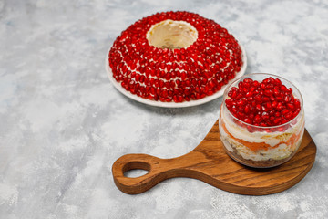 Salad Garnet bracelet. Vegetable salad with pomegranate seeds with pomegranate on concrete background