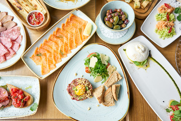 Beef tartar in the restaurant. Variety of dishes on the table. Various snacks and antipasti on the table. Restaurant menu. Italian cuisine