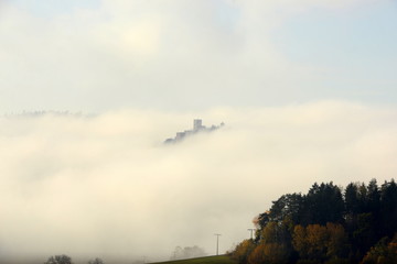 Fototapeta na wymiar Burg im Nebelmeer. Schöne Burg ragt aus Nebel hervor