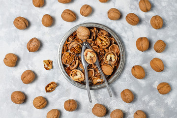 Whole walnuts in shell in food metal basket, walnut kernels. Top view on concrete background