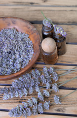 essential oil from lavender  in bottle and  dried flowers in wooden bowl © coco