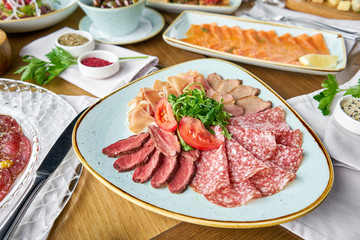 Meat plate, delicacy and Anantipasto. Salami, roast beef, Parma ham, smoked duck breast. Various snacks and antipasti on the table. Italian cuisine Restaurant menu, natural and organic food concept.