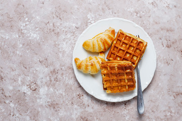 Delicious breakfast with coffee, orange juice, waffles,croissants,jam,nut paste on light...