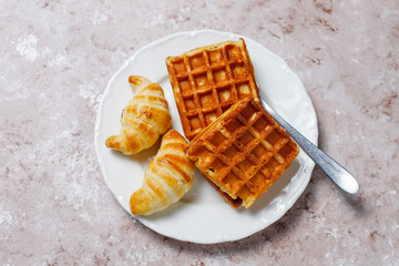 Delicious breakfast with coffee, orange juice, waffles,croissants,jam,nut paste on light background,top view