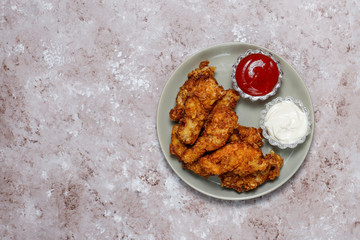 Chicken strips with ketchup and mayonnaise. top view on brown light background.