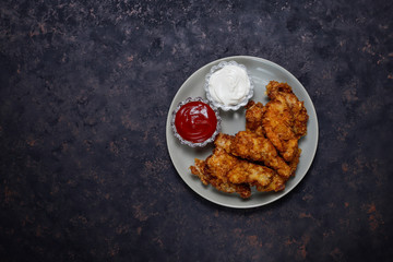 Chicken strips with ketchup and mayonnaise. top view on dark background.