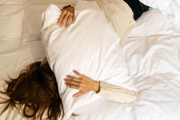 Young beautiful Asian woman too lazy to get out of bed, a woman covers her face with a pillow.