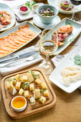 Cheese plate. Focus on delicious cheese mix with walnuts, honey on wooden table. Various snacks and antipasti on the table. Restaurant menu.