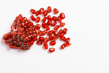 Spoon with ripe pomegranate seeds on a white isolated background.