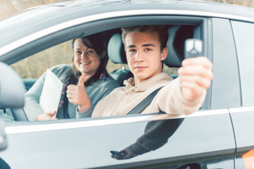 Happy student of driving school showing car keys