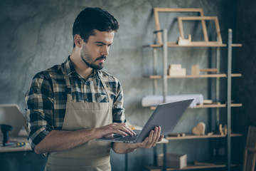 Photo of handsome guy holding notebook watching online video masterclass have free self education focused wooden business industry woodwork shop garage indoors