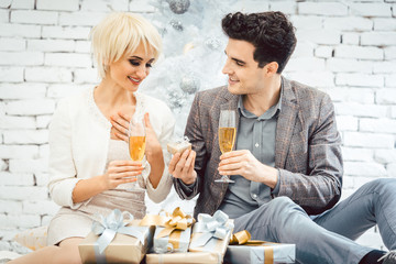 Woman and man with wine and presents in front of white Christmas tree