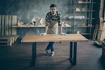 Full body photo of handsome guy master leaning hands on handmade slab table advertising good work selling website own wooden business industry woodwork shop garage indoors