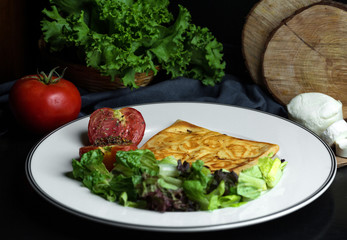 plate of crepe with cheese served with lettuce salad and grilled tomato