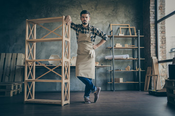 Full length photo of handsome guy showing just made book shelf handmade design wooden industry advertising own business service woodwork workshop indoors