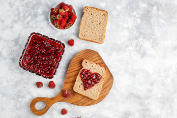 homemade raspberry jam with fresh raspberries on concrete background,top view