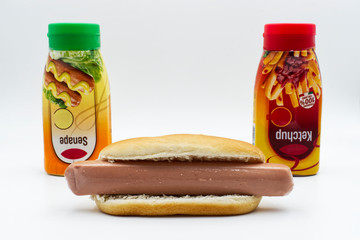 Fresh hot dog with ketchup and mustard dispenser, isolated on white background