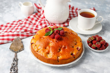 Raspberry cake with powdered sugar and fresh raspberries on a light background. Summer berry dessert.