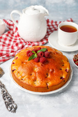 Raspberry cake with powdered sugar and fresh raspberries on a light background. Summer berry dessert.