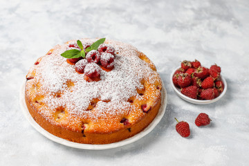 Simple cake with powdered sugar and fresh raspberries on a light background. Summer berry dessert.