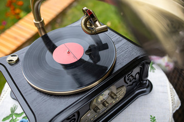 Vintage retro gramophone with vinyl record in the summer garden playing a waltz