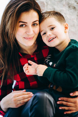 Portrait of mother with son in knitted Christmas sweaters in  play with decor. Winter New Year mood