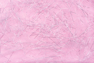 Fototapeta premium Glitter shreds. Sparkling shiny paper texture for Christmas. Silver shreds on pink background. Flat lay, copy space, top view. Winter holidays, New Year. Merry Christmas card. Space for text.