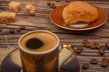Coffee Cup, croissants, brown sugar and coffee beans on wooden background. Close up.