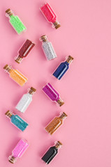 Fashion the concept of small jars with colorful confetti on a pink background