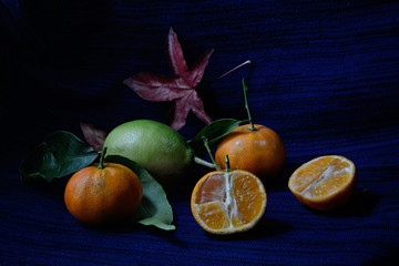 Lemon and tangerine whole and open-face on black and dark bluebackground