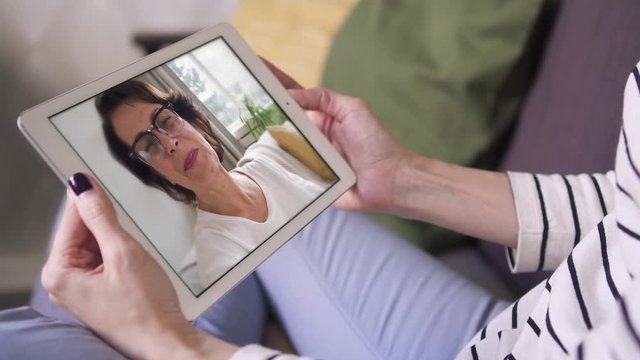 closeup of daughter sitting and chatting smiling mom via video call with tablet. facetime, family, internet, skype, online, long distance, chatting concept