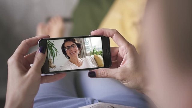 mother waving and blowing kiss to daughter through smart phone video call. facetime, online, internet, long distance, chatting concept. skype chatting with grandmother