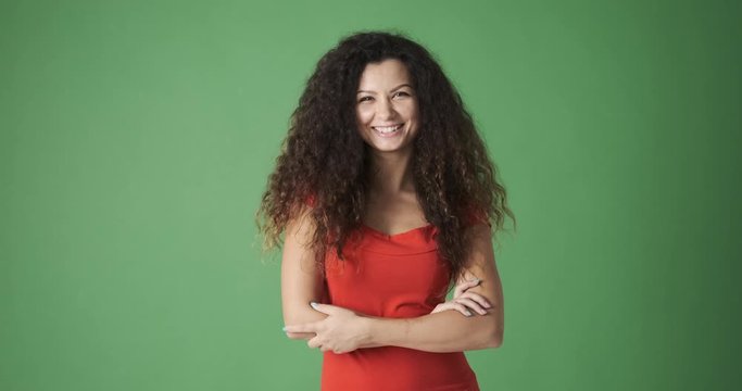 Portrait of happy young woman with arms crossed over green background