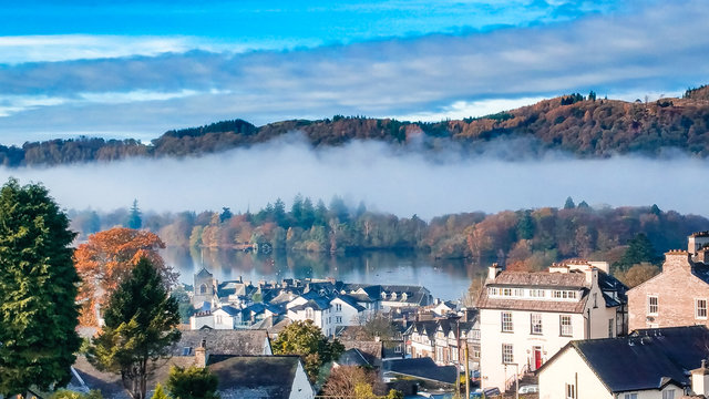 Aerial top view over Bowness On Windermere on an early morning with fog and mist rising on lake Windermere. Autumn in the Lake District, Cumbria, UK. 