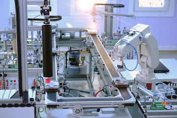 Industry 4.0 concept; artificial intelligence in smart factory prototype. Robot picks up the product from automated car on the manufacturing line. Focus on robot arm's gripper. Selective focus.