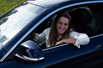 Happy dark-haired woman driving her fashionable car