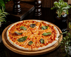 margarita pizza topped with basil leaves served on wood pizza board