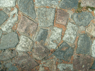 The sidewalk is paved with stone.