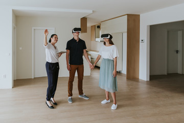 Fototapeta premium Estate agent with young couple wearing VR headsets in new apartment