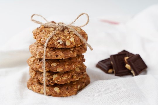 oatmeal cookies and chocolate on a white towel. White background.  Rustic style. High key in food pictures