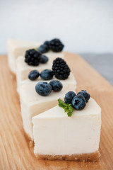 slices of classic cheesecake decorated with berries on a wooden board