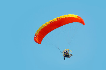 A paraglider with a motor on a sky background