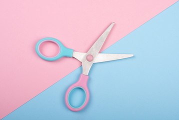 Open pink and blue scissors on the pink and blue background (minimal concept)