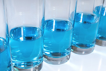 Row of glasses filled with blue liquid